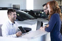 Smiling professional car dealer showing an offer to happy buyers stock image Smiling professional car dealer showing an offer to happy buyers stock image