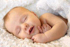 Smiling Sleeping Newborn Baby Girl Wrapped in White Blanket