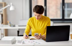 Smiling ui designer using smartphone at office stock photos Smiling ui designer using smartphone at office stock photos