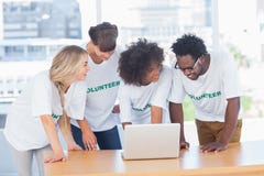 Smiling volunteers working together on a laptop royalty free stock photography Smiling volunteers working together on a laptop royalty free stock photography
