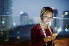 Smiling young woman using a smartphone in the evening cityscape stock image Smiling young woman using a smartphone in the evening cityscape stock image