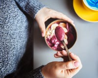 Smoothie Acai, granola, семена, свежие фрукты в деревянном шаре в женских руках на серой таблице Еда здорового шара завтрака top стоковое фото rf Smoothie Acai, granola, семена, свежие фрукты в деревянном шаре в женских руках на серой таблице Еда здорового шара завтрака top стоковое фото rf