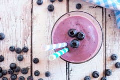 Smoothie de myrtille dans un verre avec des baies, vue supérieure au-dessus de bois blanc rustique images stock Smoothie de myrtille dans un verre avec des baies, vue supérieure au-dessus de bois blanc rustique images stock