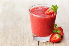 Smoothie клубники в стекле украшенном с листьями мяты на деревенской предпосылке, соке свежих фруктов, еде вытрезвителя Стоковые Изображения Smoothie клубники в стекле украшенном с листьями мяты на деревенской предпосылке, соке свежих фруктов, еде вытрезвителя Стоковые Изображения