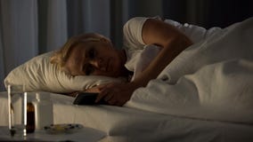 Smutna starsza kobieta patrzeje telefonu łgarskiego łóżko, nocy samotność, starości choroba obrazy stock Smutna starsza kobieta patrzeje telefonu łgarskiego łóżko, nocy samotność, starości choroba obrazy stock
