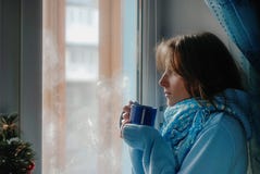 Smutna wzburzona osamotniona piękna młoda kobieta marzy blisko zamarzniętego okno w pulowerze zdjęcie stock Smutna wzburzona osamotniona piękna młoda kobieta marzy blisko zamarzniętego okno w pulowerze zdjęcie stock