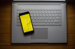Snapchat app on a broken cell phone sitting on a laptop stock image Snapchat app on a broken cell phone sitting on a laptop stock image
