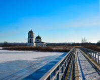 Snow-covered lake with a metal bridge towards church stock image Snow-covered lake with a metal bridge towards church stock image