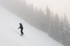 Snowboarder daalt van een hoge berg op een helling bij de winter koude dag royalty-vrije stock fotografie Snowboarder daalt van een hoge berg op een helling bij de winter koude dag royalty-vrije stock fotografie