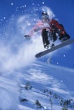 Snowboarder no meio do ar com o pó da neve que arrasta atrás imagens de stock Snowboarder no meio do ar com o pó da neve que arrasta atrás imagens de stock