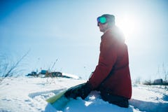 Snowboarder сидя на снежном наклоне в солнечный день Стоковые Изображения RF Snowboarder сидя на снежном наклоне в солнечный день Стоковые Изображения RF