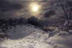Snowy e la cima congelata della collina con cielo notturno nuvoloso e della luce della luna con la città si accende sui precedent immagini stock Snowy e la cima congelata della collina con cielo notturno nuvoloso e della luce della luna con la città si accende sui precedent immagini stock