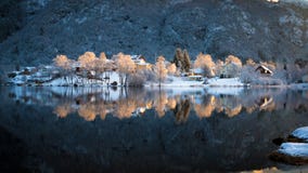 Snowy ed alberi brillanti variopinti e case riflessi nel lago Haukeland nella periferia di Bergen nell'inverno immagine stock libera da diritti Snowy ed alberi brillanti variopinti e case riflessi nel lago Haukeland nella periferia di Bergen nell'inverno immagine stock libera da diritti