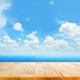 Sobremesa de madera en la agua de mar azul y el fondo brillante del cielo del verano