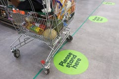 Social distancing marks on supermarket floor intended to stop or slow down the spread of a contagious Coronavirus COVID-19