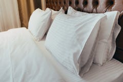 Comfortable soft pillows on the bed. Close-up white bedding sheets and pillow on light wall room background. Fresh bed concept royalty free stock images Comfortable soft pillows on the bed. Close-up white bedding sheets and pillow on light wall room background. Fresh bed concept royalty free stock images