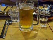 Soju-Gläser voll vom soju und ein Bierglas voll vom Bier mit koreanischen Beilagen an der Jahresabschluss- Partei in Korea lizenzfreie stockfotos Soju-Gläser voll vom soju und ein Bierglas voll vom Bier mit koreanischen Beilagen an der Jahresabschluss- Partei in Korea lizenzfreie stockfotos