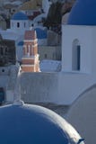 Solbelyst kyrklig tornspira i den Oia staden på den grekiska ön av Santorini arkivbilder Solbelyst kyrklig tornspira i den Oia staden på den grekiska ön av Santorini arkivbilder
