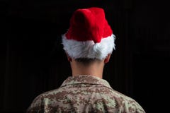Soldado novo que veste a posição do chapéu de Santa no fundo preto fotos de stock Soldado novo que veste a posição do chapéu de Santa no fundo preto fotos de stock