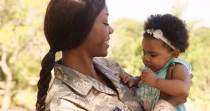 Soldier mother holding her daughter in a park