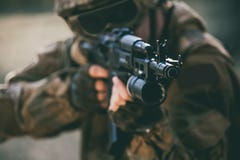 The soldier in the performance of tasks in camouflage, protective gloves, helmet and tinted glasses holding a machine gun royalty free stock photography The soldier in the performance of tasks in camouflage, protective gloves, helmet and tinted glasses holding a machine gun royalty free stock photography