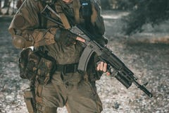 The soldier in the performance of tasks in camouflage and protective gloves holding a gun. royalty free stock photography The soldier in the performance of tasks in camouflage and protective gloves holding a gun. royalty free stock photography