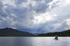 Solstrålar som bryter till och med stormmoln över bergsjön Arkivfoton Solstrålar som bryter till och med stormmoln över bergsjön Arkivfoton