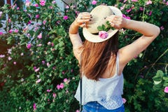 Sombrero que lleva de la muchacha joven del inconformista que camina por las rosas florecientes La mujer goza de las flores en pa imagenes de archivo Sombrero que lleva de la muchacha joven del inconformista que camina por las rosas florecientes La mujer goza de las flores en pa imagenes de archivo