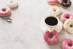 Sone pink and white donuts with cup of coffee over white stone t stock image Sone pink and white donuts with cup of coffee over white stone t stock image