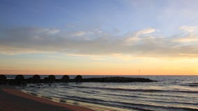 Sonnenuntergang auf dem Strand mit einem Wellenbrecher stock footage Sonnenuntergang auf dem Strand mit einem Wellenbrecher stock footage