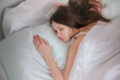 Sonno castana della giovane donna a letto Immagine Stock Libera da Diritti Sonno castana della giovane donna a letto Immagine Stock Libera da Diritti