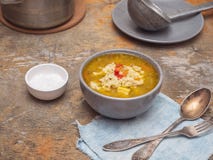 Sopa con las bolas de masa hervida en una placa gris profunda en una tabla rústica En el fondo es un cazo con la sopa, una cuchar fotos de archivo libres de regalías Sopa con las bolas de masa hervida en una placa gris profunda en una tabla rústica En el fondo es un cazo con la sopa, una cuchar fotos de archivo libres de regalías