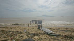 Soporte de la gente en la playa delante de la navegación quebrada del edificio en el mar Soporte de la gente en la playa delante de la navegación quebrada del edificio en el mar