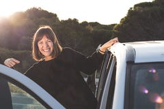 Sorridere della ragazza, tenente sopra ad una porta di automobile Concetto del viaggio e della libertà immagine stock Sorridere della ragazza, tenente sopra ad una porta di automobile Concetto del viaggio e della libertà immagine stock