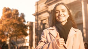 Sorridere femminile motivato felice vicino alla costruzione dell'universit?, mostrante il pollice in su immagine stock Sorridere femminile motivato felice vicino alla costruzione dell'universit?, mostrante il pollice in su immagine stock