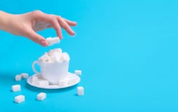 Sort de sucre dans une tasse Main mettant un cube en sucre image libre de droits Sort de sucre dans une tasse Main mettant un cube en sucre image libre de droits