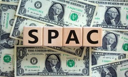 SPAC, special purpose acquisition company symbol. Wooden cubes with word `SPAC` on beautiful background from dollar bills, copy