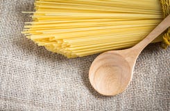 Spaghetti uncooked and spoon wood. On gunny royalty free stock photos Spaghetti uncooked and spoon wood. On gunny royalty free stock photos
