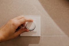 Sparande energibegrepp: Mänsklig hand som ner vänder den elektriska ljusa ljusdämpareströmbrytaren royaltyfri fotografi Sparande energibegrepp: Mänsklig hand som ner vänder den elektriska ljusa ljusdämpareströmbrytaren royaltyfri fotografi