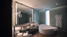 Specchio del bagno costoso e vasca interni e enormi, mucchio bianco degli asciugamani Specchio del bagno costoso e vasca interni e enormi, mucchio bianco degli asciugamani