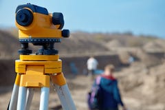 Special device level for surveyor builders, geodesy equipment close up in front of a ground work with people on blurred backgrou stock photo Special device level for surveyor builders, geodesy equipment close up in front of a ground work with people on blurred backgrou stock photo