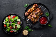 Spiedi arrostiti della carne, kebab ed insalata di verdure sana del pomodoro, del cetriolo, della cipolla, degli spinaci, della l immagini stock Spiedi arrostiti della carne, kebab ed insalata di verdure sana del pomodoro, del cetriolo, della cipolla, degli spinaci, della l immagini stock