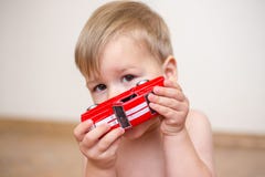 Spielt jähriger Junge zwei mit einem roten Spielzeugauto lizenzfreies stockfoto Spielt jähriger Junge zwei mit einem roten Spielzeugauto lizenzfreies stockfoto