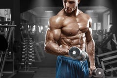 Spiermens die in gymnastiek uitwerken die oefeningen met domoren doen bij bicepsen, sterke mannelijke naakte torsoabs Stock Afbeelding Spiermens die in gymnastiek uitwerken die oefeningen met domoren doen bij bicepsen, sterke mannelijke naakte torsoabs Stock Afbeelding