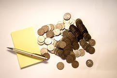 Yellow notebook with pen and mountain of mettalical coins on white background stock image Yellow notebook with pen and mountain of mettalical coins on white background stock image