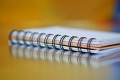 Spiral-bound notebook on a golden and blue background with reflection. Work in the office. Research and training royalty free stock images Spiral-bound notebook on a golden and blue background with reflection. Work in the office. Research and training royalty free stock images