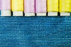 Spoelen van roze en gele naaiende draad op blauw denim met exemplaarruimte royalty-vrije stock fotografie Spoelen van roze en gele naaiende draad op blauw denim met exemplaarruimte royalty-vrije stock fotografie