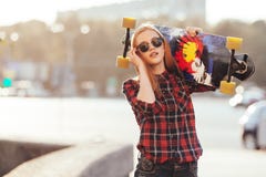 Sport happy girl posing in summer with skateboard. Stylish lucky hipster woman with colorful longboard in sunset in Stock Photo Sport happy girl posing in summer with skateboard. Stylish lucky hipster woman with colorful longboard in sunset in Stock Photo