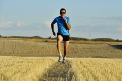 Sport man with sunglasses running outdoors on straw field ground in frontal perspective stock photography Sport man with sunglasses running outdoors on straw field ground in frontal perspective stock photography