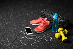 Sport shoes, dumb-bells, pilates mat, blue bottle, and phone with headphones on a black background. Training concept. Royalty Free Stock Image Sport shoes, dumb-bells, pilates mat, blue bottle, and phone with headphones on a black background. Training concept. Royalty Free Stock Image
